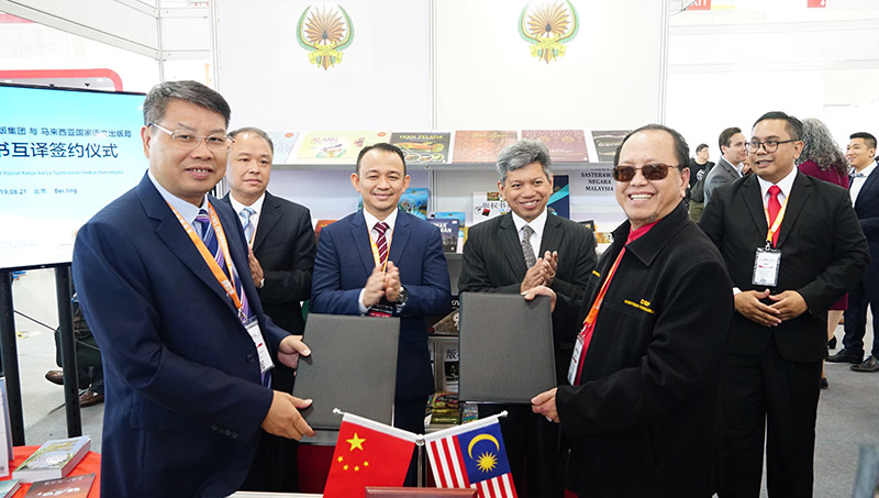 廣西師范大學(xué)出版社集團黨委書(shū)記、董事長(cháng)張藝兵（左前一）與馬來(lái)西亞國家語(yǔ)文出版局理事長(cháng)Datuk Abang Sallehuddin Abang Shokeran交換簽約文件（陳子鋒攝）.jpg